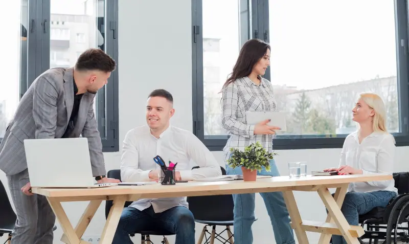Four team members share ideas around table whilebusiness directory helps your company reach new local customers